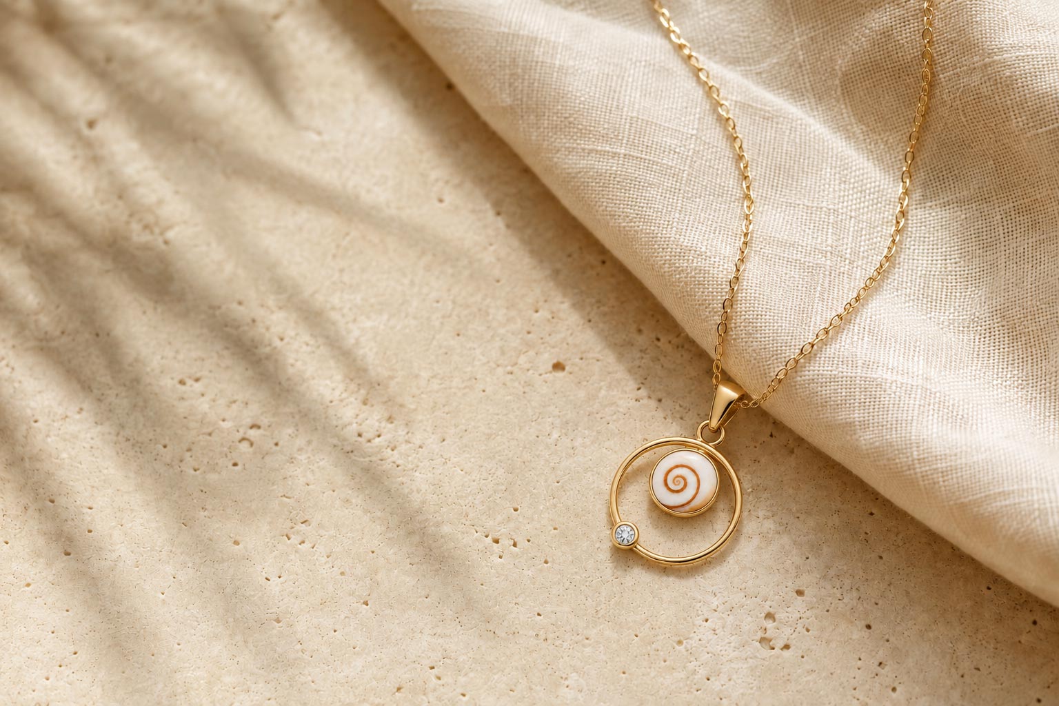 Pendentif doré OSL-Corsica avec Œil de Sainte-Lucie, posé sur du lin et de la pierre claire